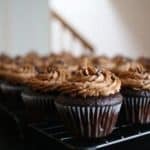 Chocolate cupcakes with chocolate frosting on a metal baking rack