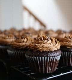 Chocolate cupcakes with chocolate frosting on a metal baking rack