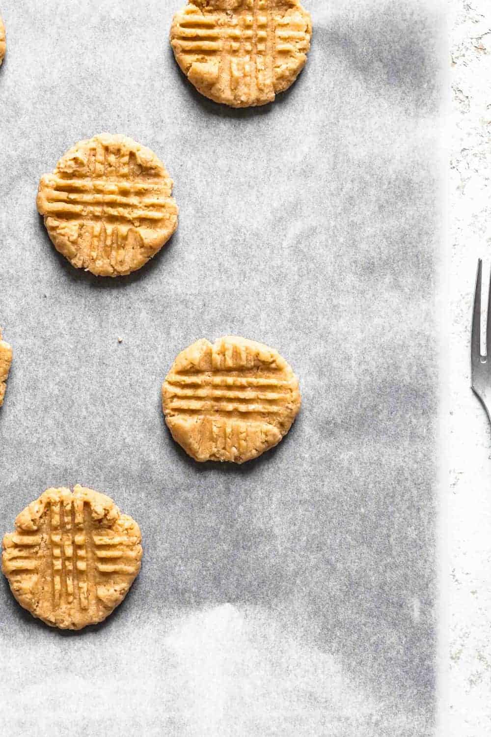 Unbaked peanut butter cookies on a parchment-lined baking sheet