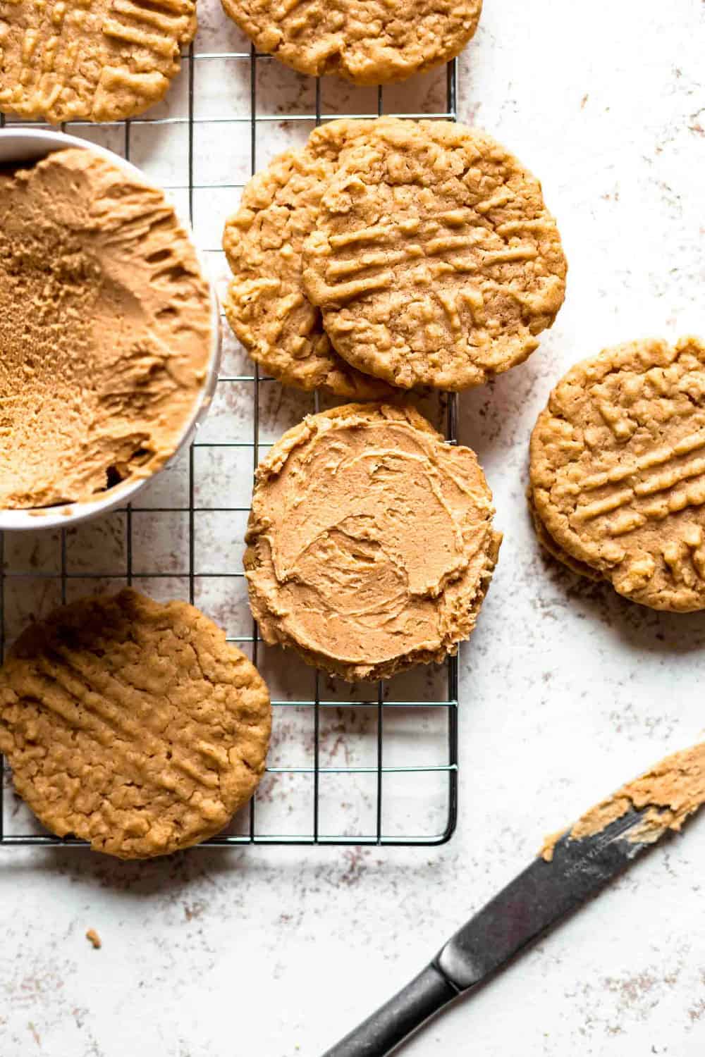 Bowl of peanut butter filling surrounded by peanut butter cookies. One of the cookies is topped with peanut butter filling