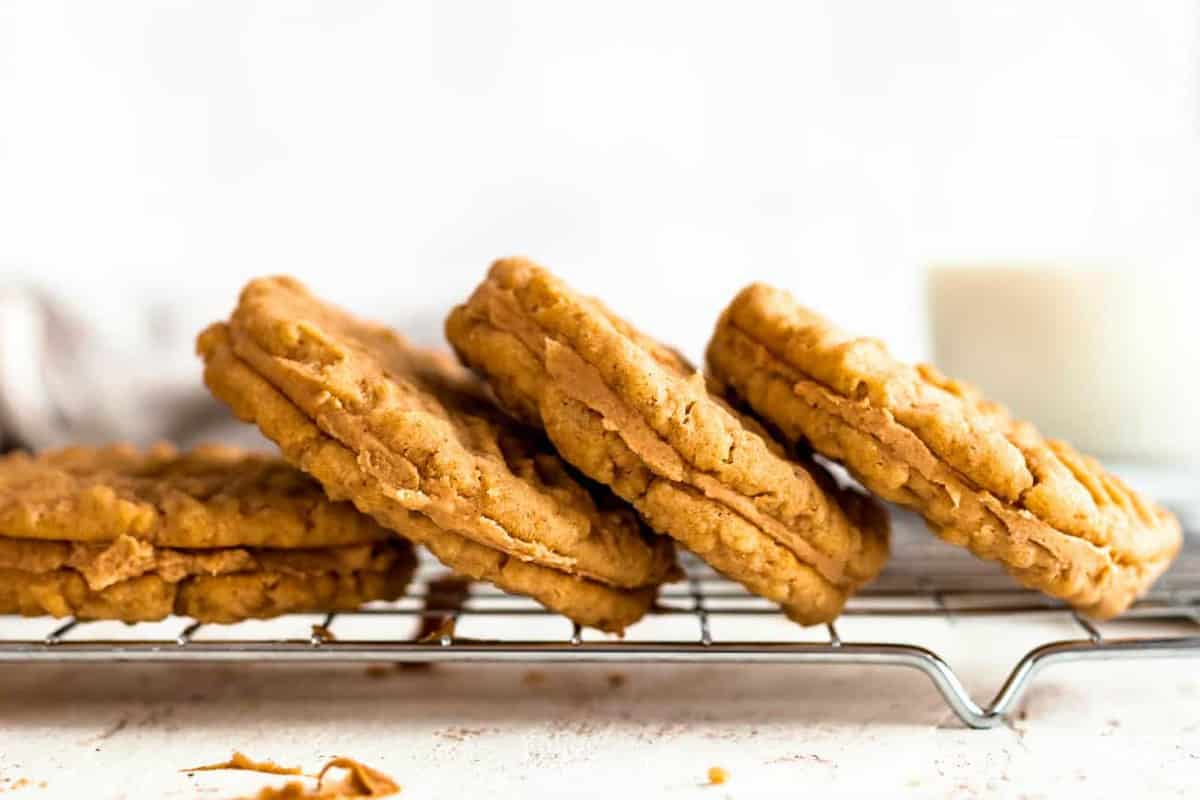 Close up of four peanut butter sandwich cookies laying on their side on a baking rack