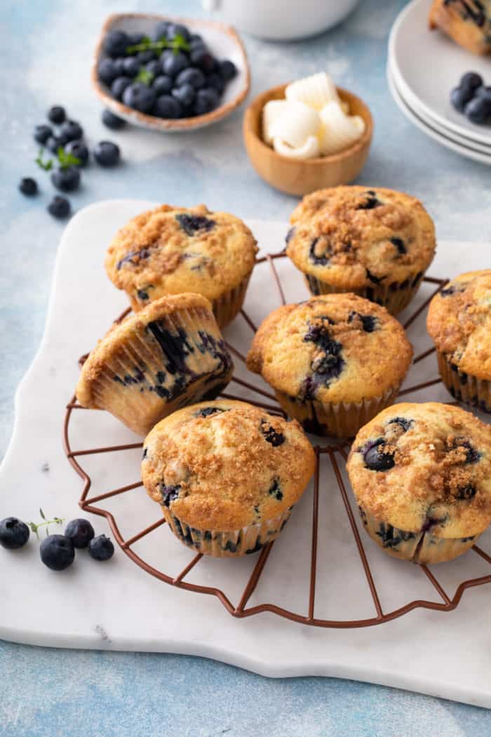 Blueberry crumb muffins arranged on a wire rack to cool.