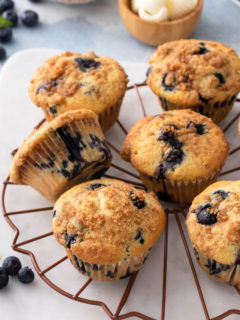 Blueberry crumb muffins scattered on a wire cooling rack.