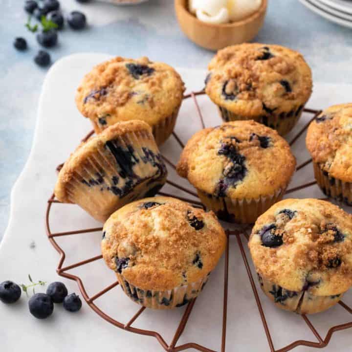 Blueberry crumb muffins scattered on a wire cooling rack.