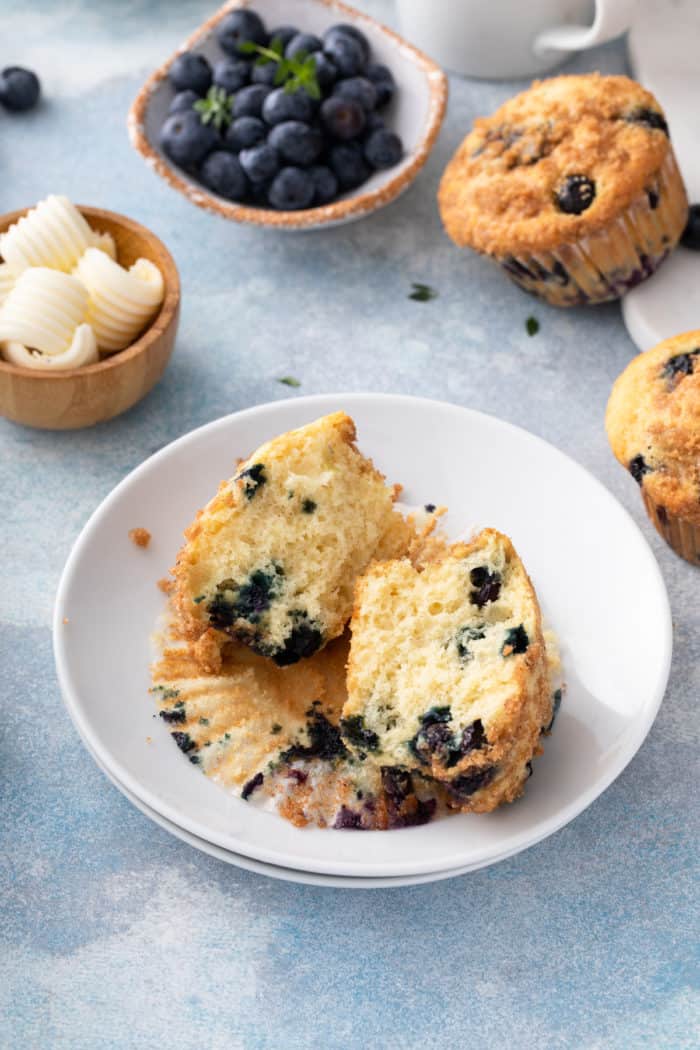 Blueberry crumb muffin cut in half on a white plate.