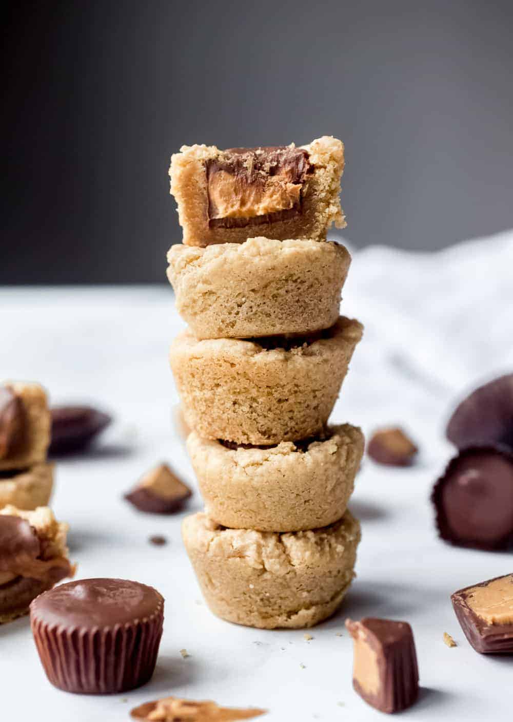 5 stacked peanut butter cup cookies with the top cookie cut in half to show the peanut butter center