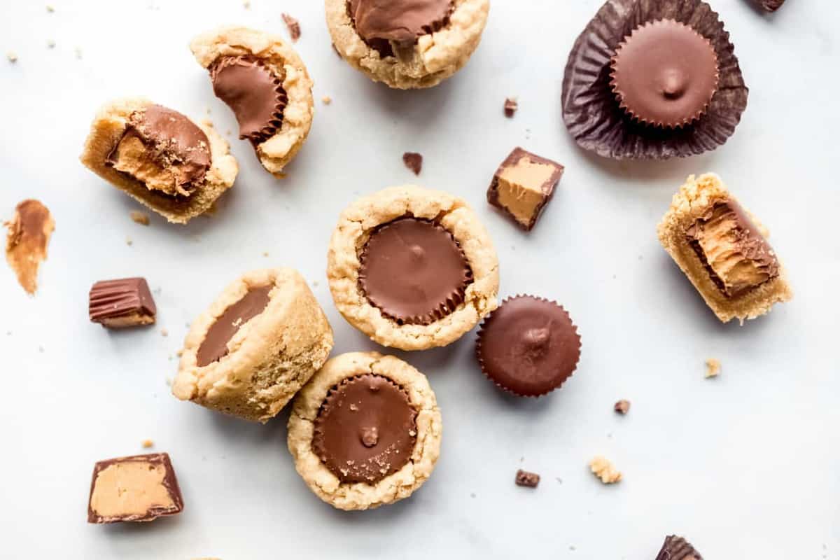 Peanut Butter Cup Cookies scattered on a white surface with mini peanut butter cups