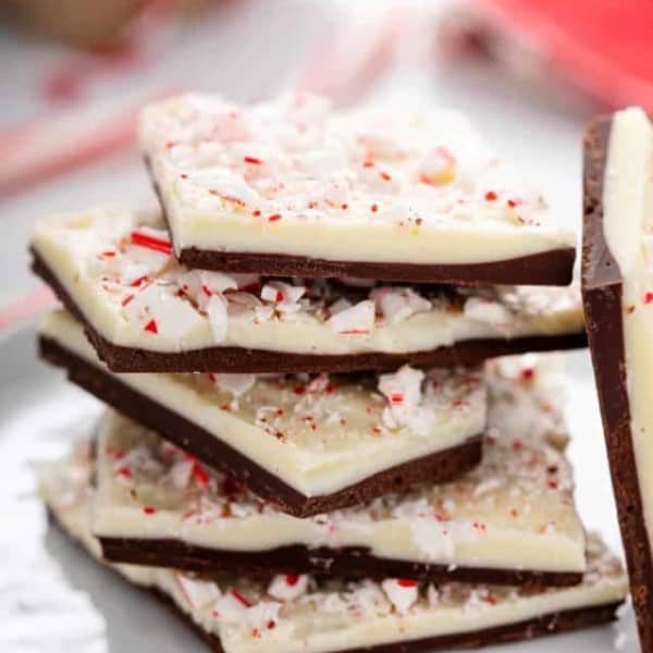 Pieces of peppermint bark stacked on a white plate.