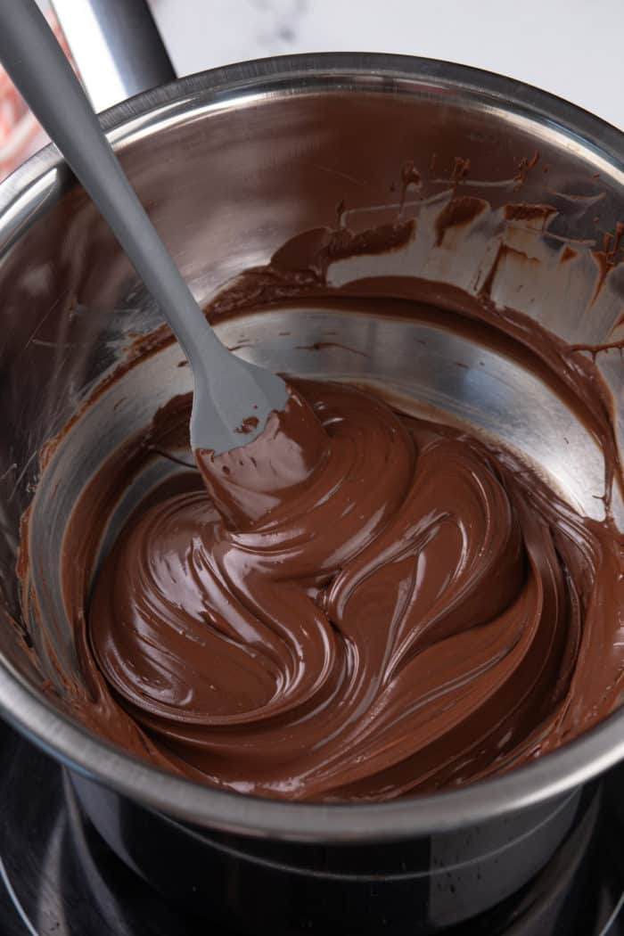 Dark chocolate being melted in a metal bowl.
