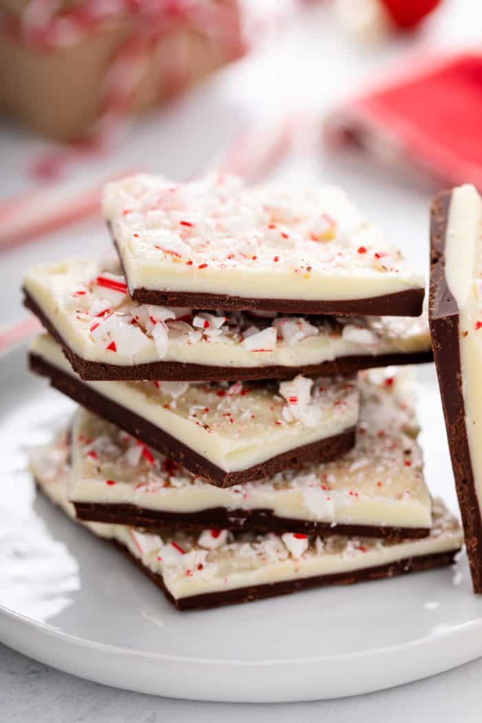 Pieces of peppermint bark stacked on a white plate.