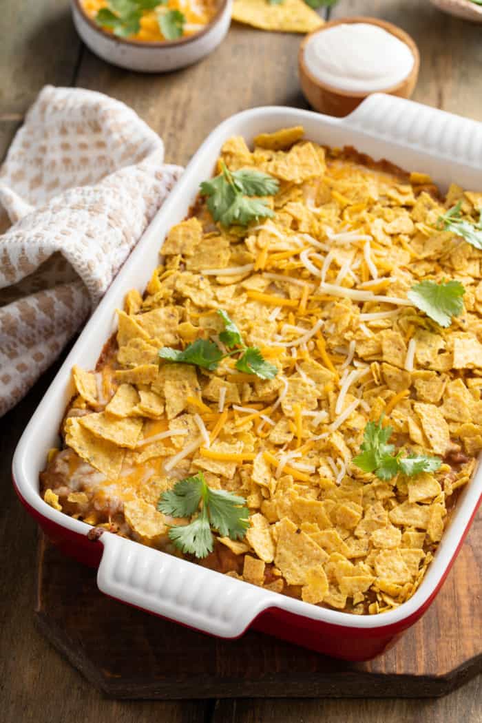 White casserole dish filled with baked taco casserole, garnished with fresh cilantro.