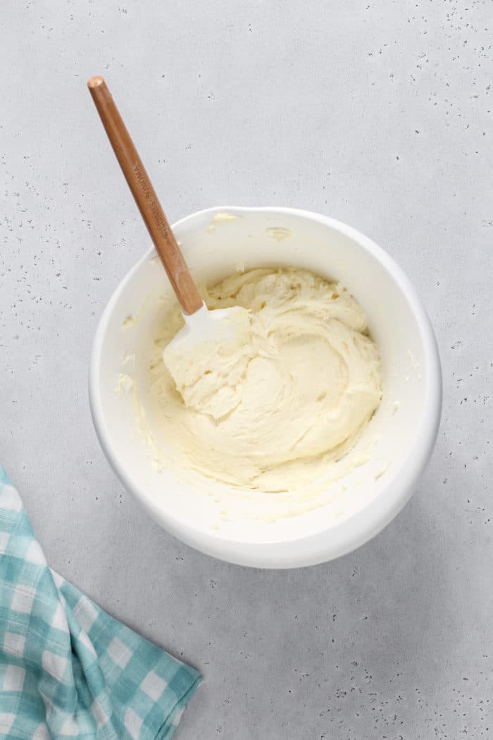 Buttercream frosting for sugar cookie bars in a white mixing bowl on a gray countertop