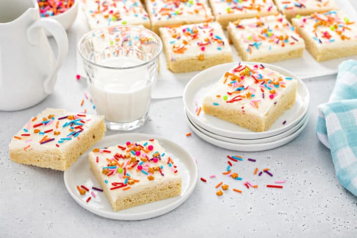 Sugar cookie bars scattered around a countertop next to a glass of milk