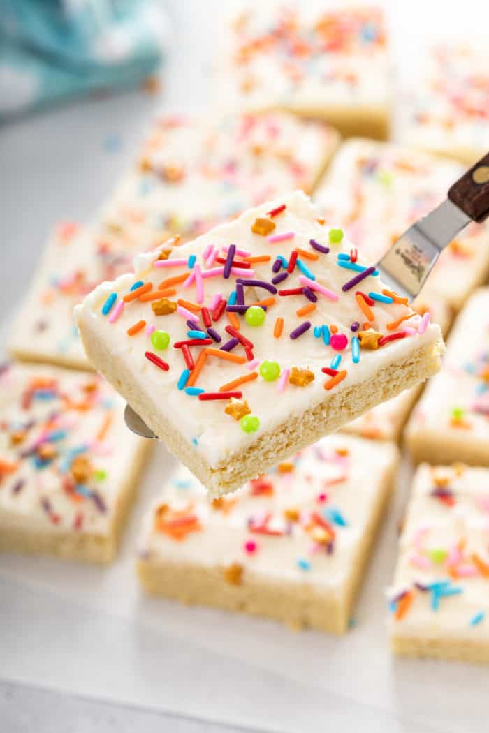 Spatula holding up a cut sugar cookie bar topped with colorful sprinkles