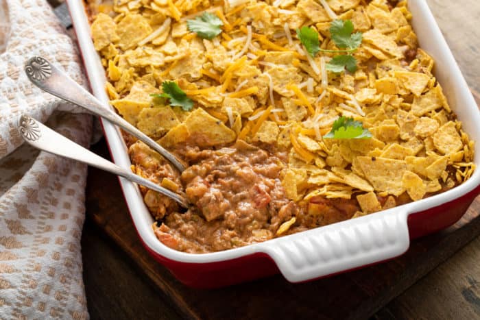 Spoons in the corner of a casserole dish of baked taco casserole.