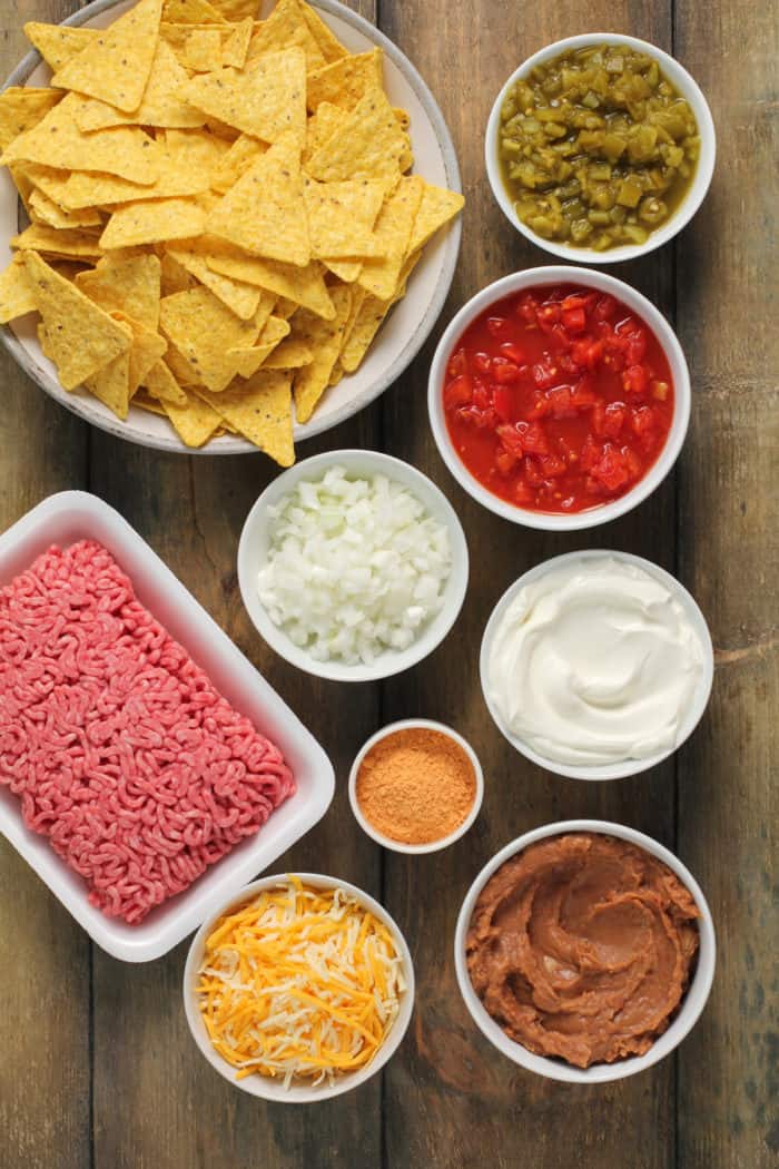 Ingredients for taco casserole arranged on a wooden countertop.