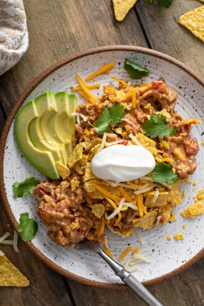 Close up view of taco casserole on a stoneware plate, with a bite about to be picked up with a fork.