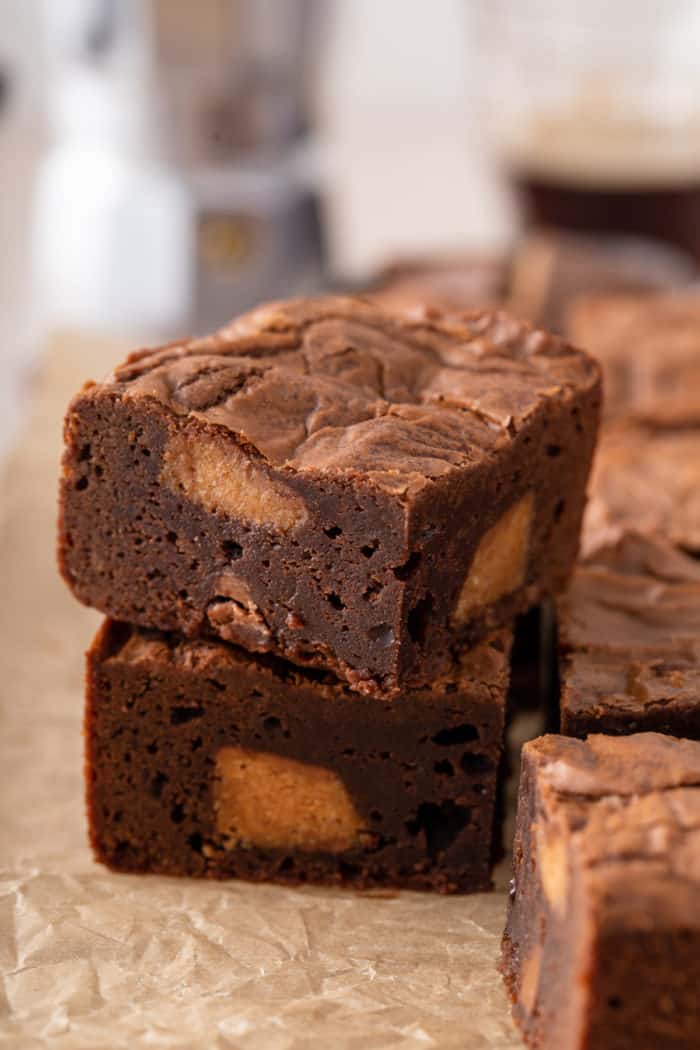Two stacked peanut butter cup brownies on a piece of parchment paper.