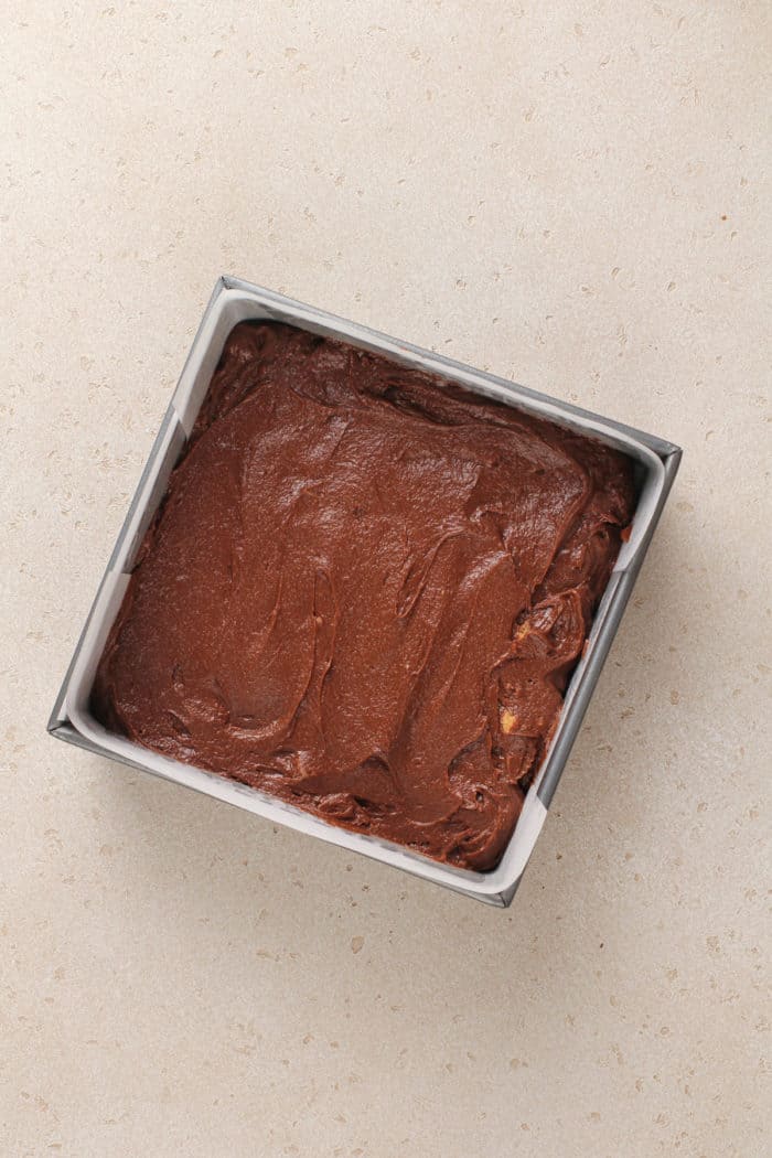 Peanut butter cup brownie batter spread into a square pan, ready to go in the oven.