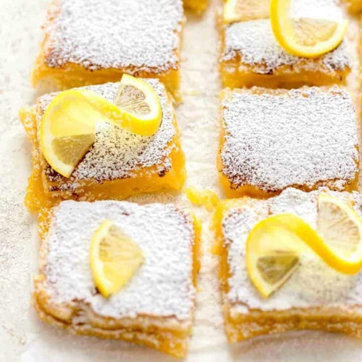Overhead view of homemade lemon bars, sliced and topped with powdered sugar and lemon slices