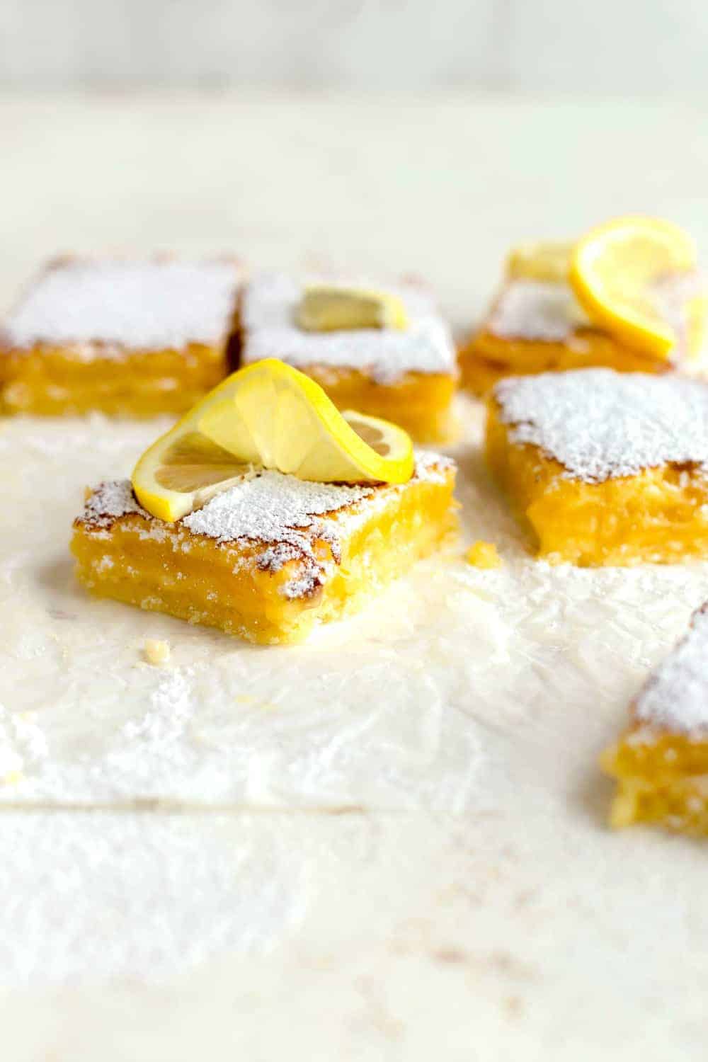 45-degree view of homemade lemon bars topped with powdered sugar and lemon twists