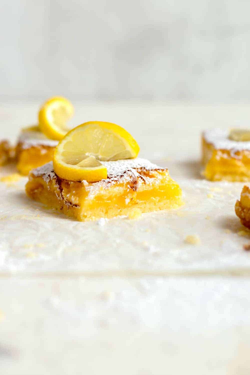 Side view of homemade lemon bars topped with a lemon twist