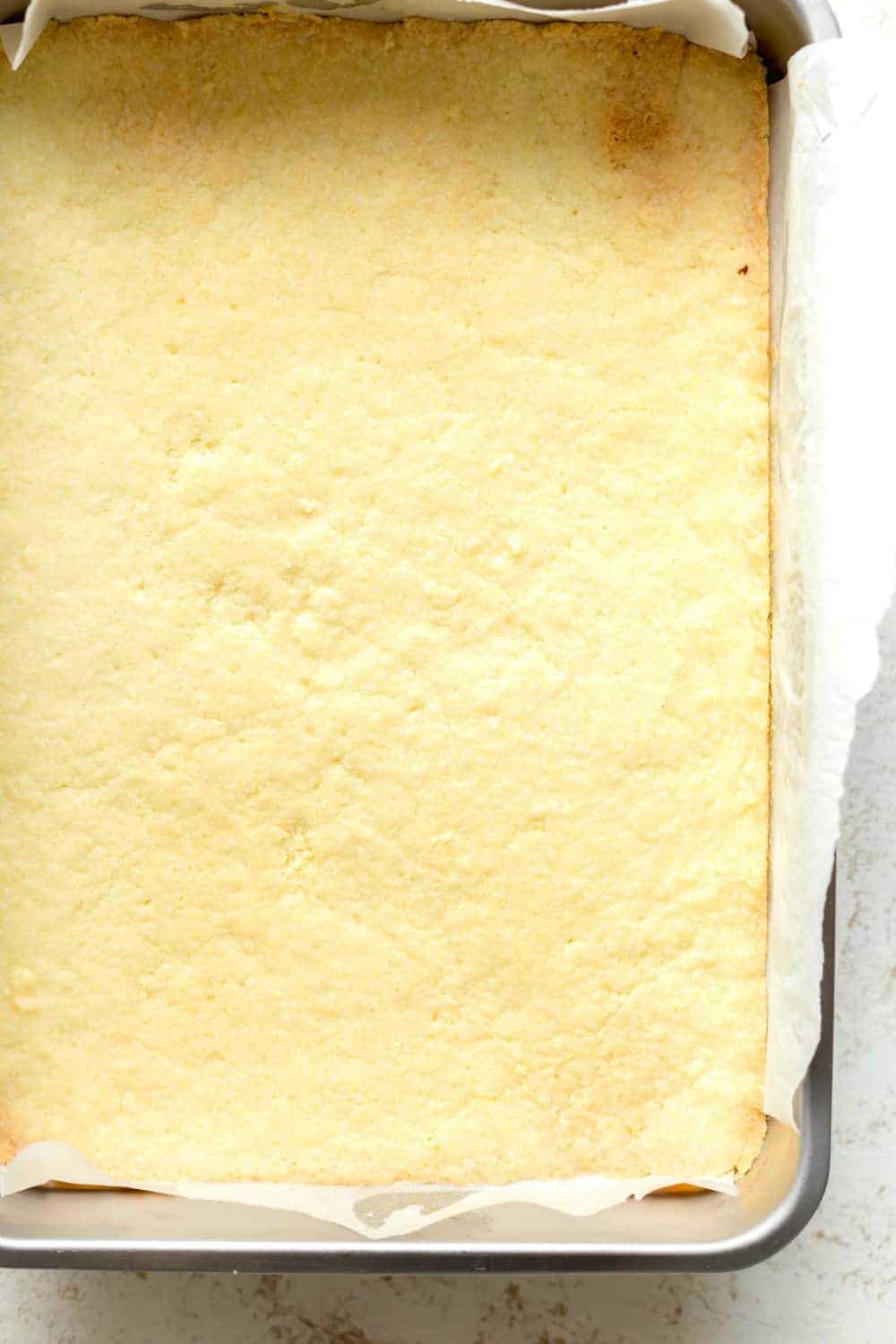 Freshly baked homemade lemon bars in parchment-lined pan