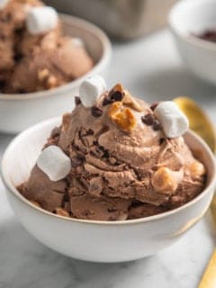 White bowl filled with rocky road ice cream, topped with mini marshmallows and peanuts.