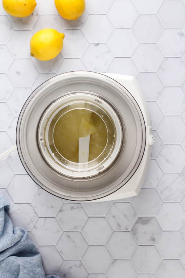 Ice cream maker churning lemon sorbet on a white tile countertop.