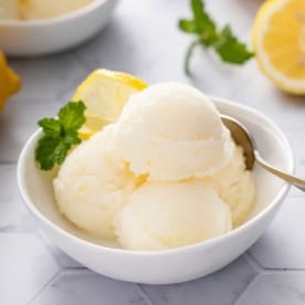 White bowl filled with scoops of lemon sorbet.