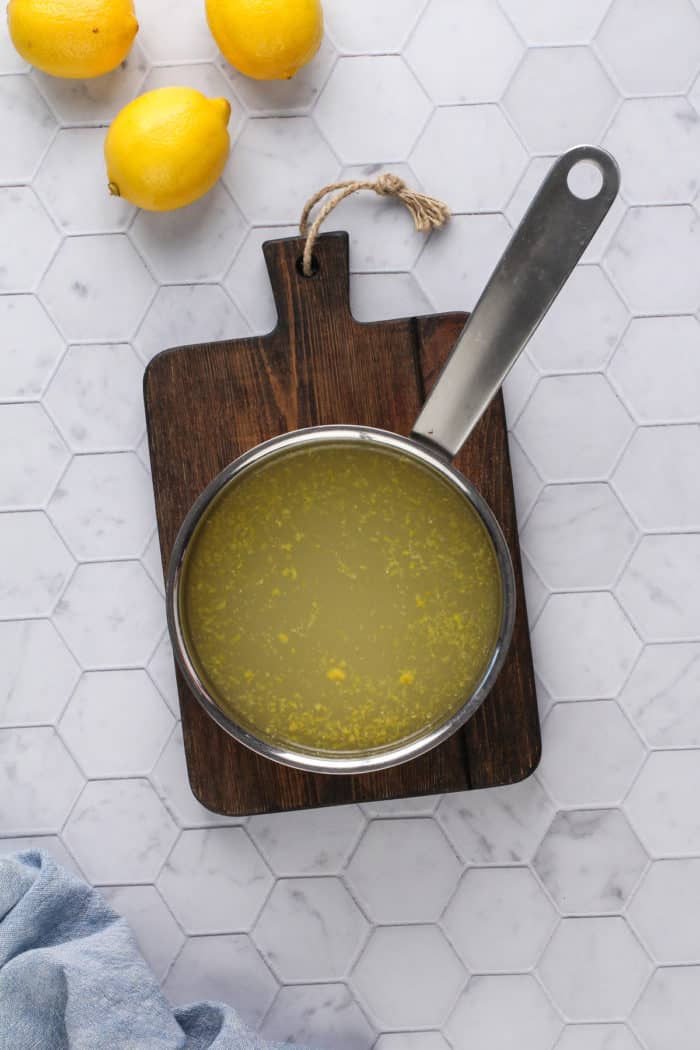 Lemon sorbet base in a sauce pan set on a wooden board.