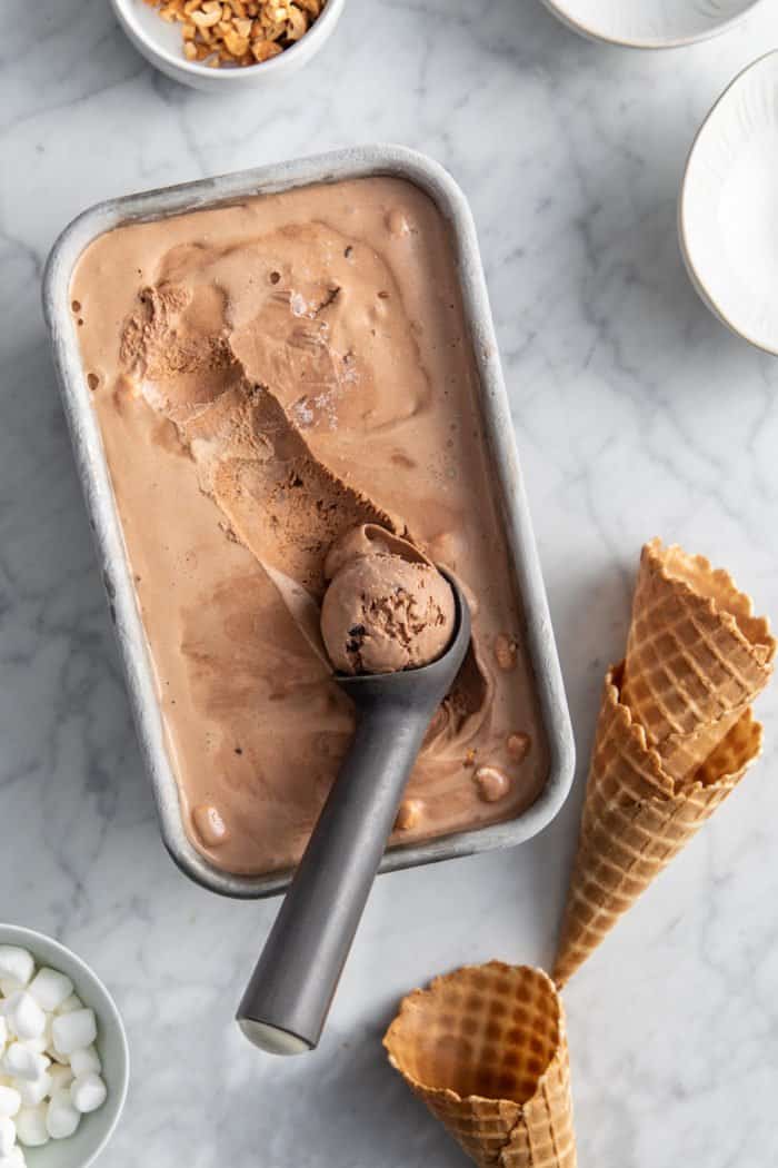 Rocky road ice cream being scooped out of a metal container.