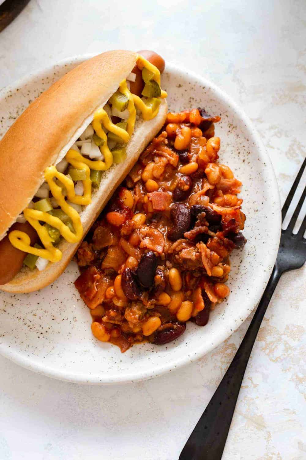 Close up of a plate with old fashioned baked beans and a hot dog