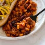 Spoon scooping up old fashioned baked beans from a plate