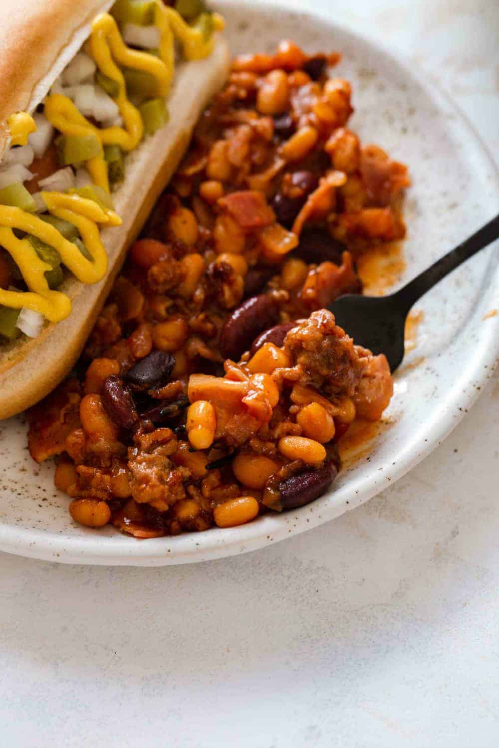 Spoon scooping up old fashioned baked beans from a plate