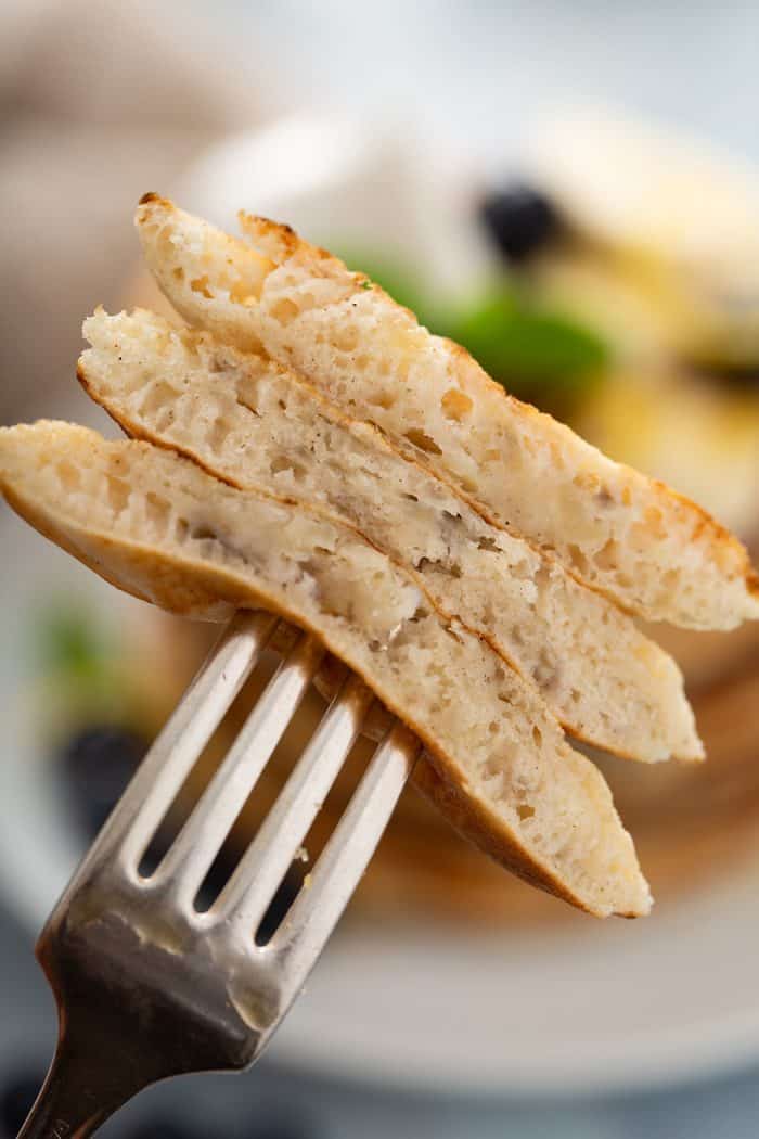 Fork holding up a bite of 3 banana pancakes so you can see the texture inside