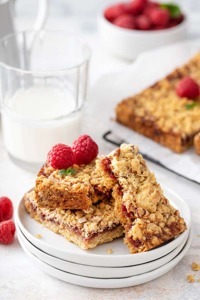 Raspberry bars on a white plate, with the top bar broken in half