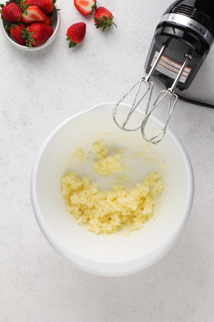 Butter and sugar creamed together in a white bowl for strawberry banana muffins.