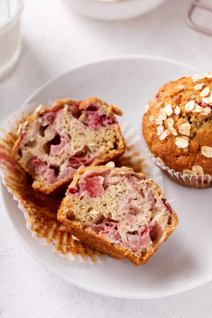 Strawberry banana muffin cut in half on a white plate.