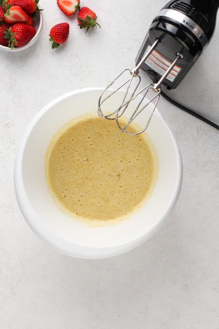 Eggs beaten into the wet ingredients for strawberry banana muffins.