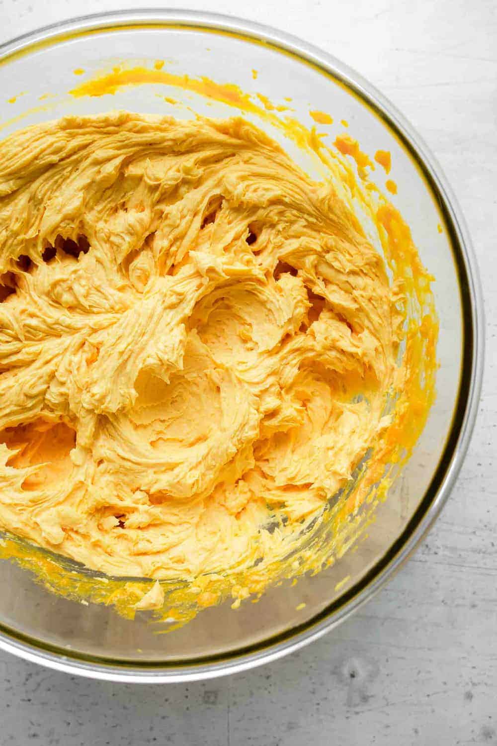 Butter, sugar, pumpkin and eggs creamed together in a bowl for making pumpkin cookies