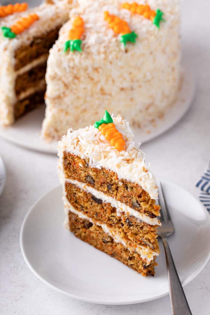 Close up of a slice of 3-layered carrot cake on a white plate.