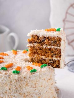 Cake server pulling a slice of carrot cake out of the whole cake.