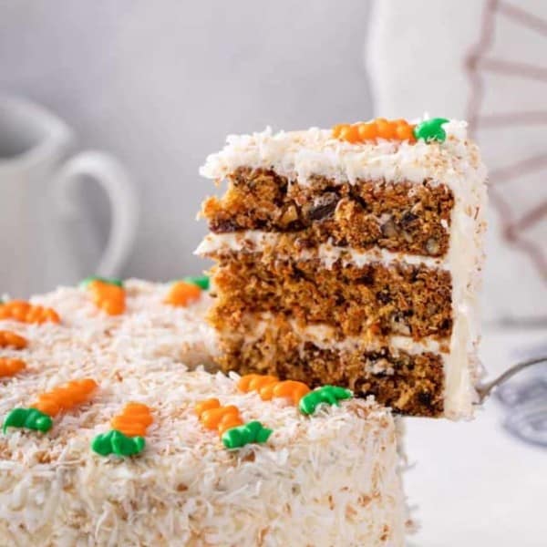 Cake server pulling a slice of carrot cake out of the whole cake.