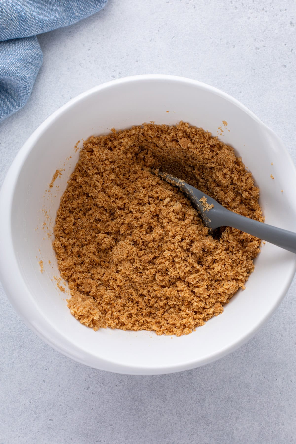 Graham cracker crumbs mixed with butter in a bowl.