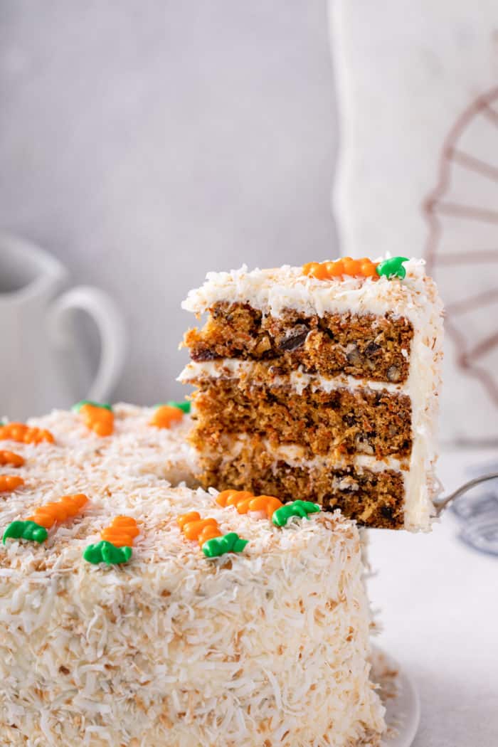 Cake server pulling a slice of carrot cake out of the whole cake.