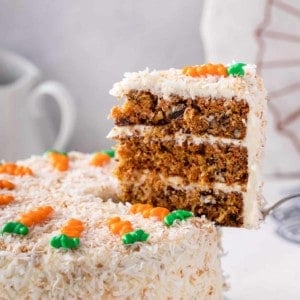 Cake server holding up a slice of 3-layered carrot cake.