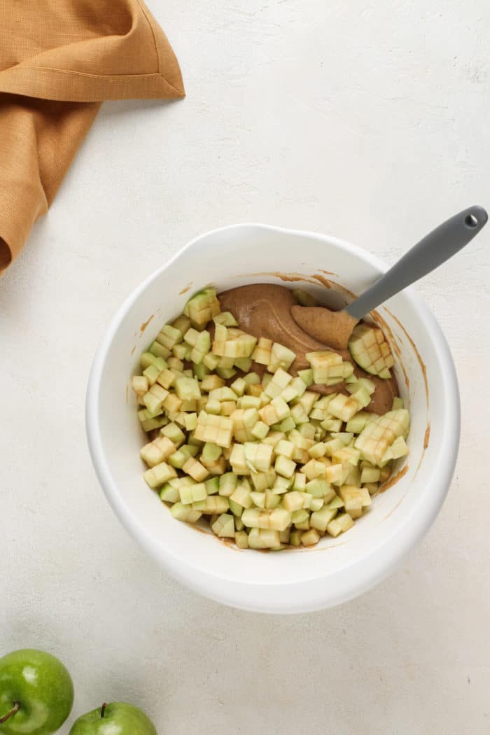 Diced apples being added to spice cake batter for easy apple bundt cake.