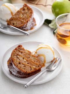 Slice of easy apple bundt cake and a scoop of ice cream on a white plate, both drizzled with caramel sauce.