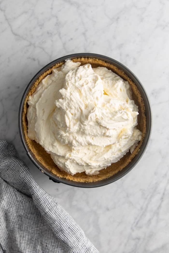 No-bake cheesecake filling spooned into a graham cracker crust.